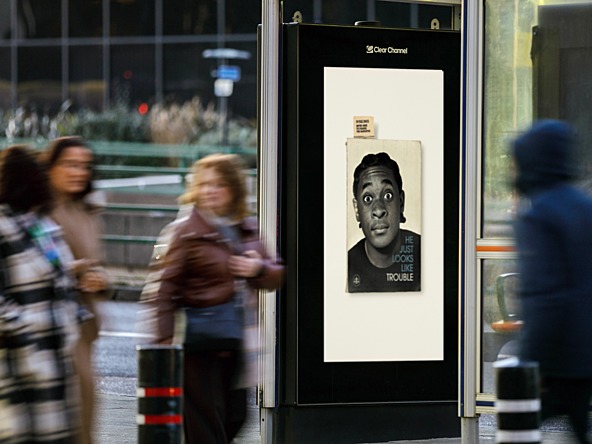 M&C Saatchi Changing Narratives advertising campaign on an outdoor digital ad screen on a bus stop, featuring a young black man on a book cover with the line 'He just looks like trouble'